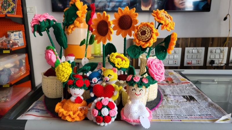 A table full of handmade crochet flowers, dolls and toys